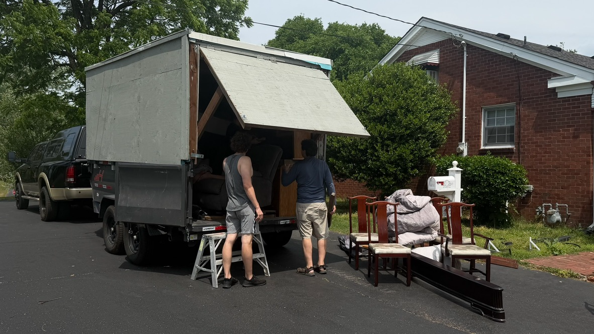Hauling Patriots crew unloading furniture from a 16-foot enclosed moving trailer on a Nashville moving job